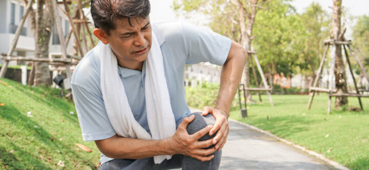 Asian senior man falling down and getting knee hurt from walking or jogging exercise at the park. pain and injury for elderly insurance concept